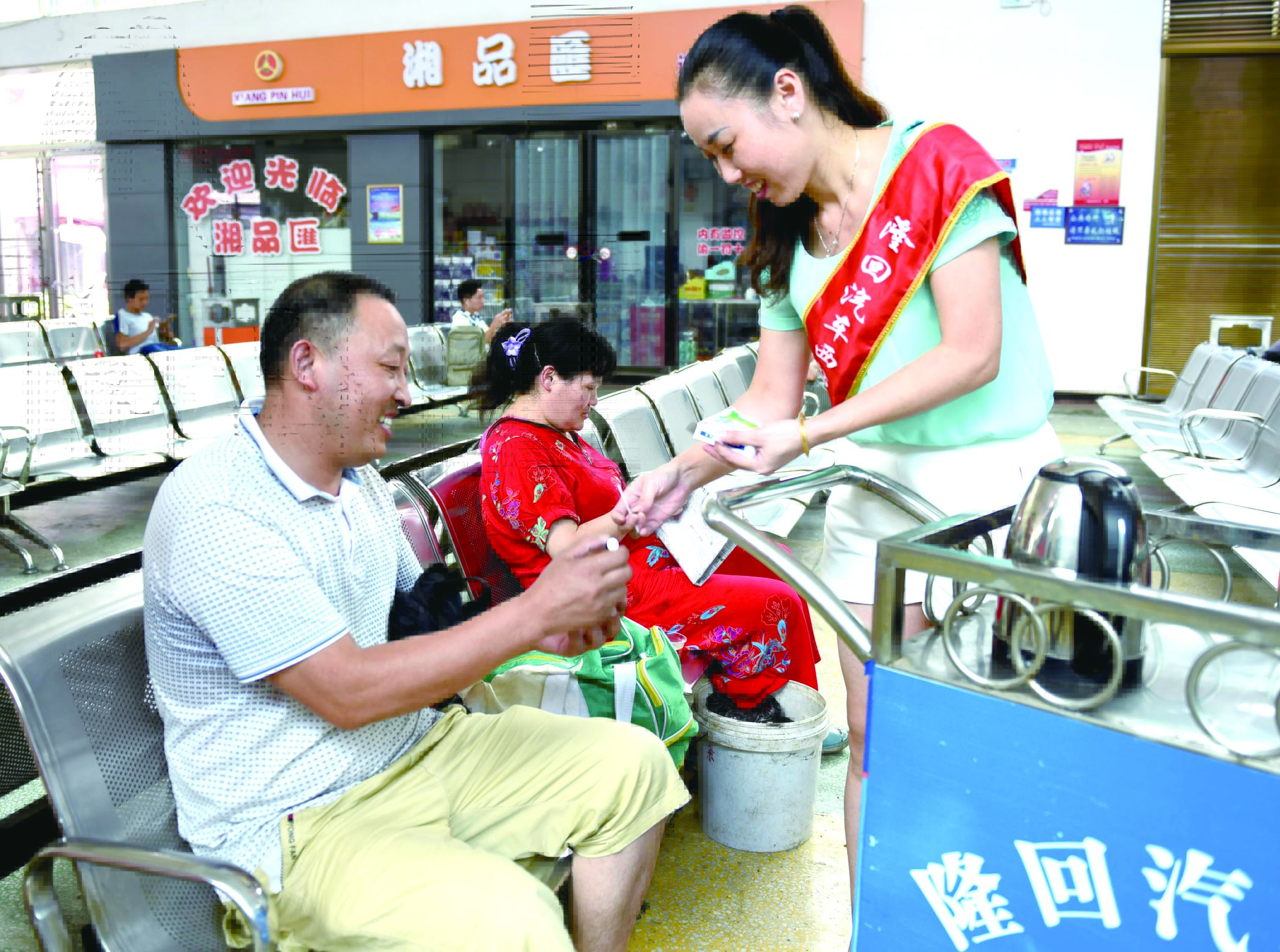 隆回分公司汽車西站工作人員正在為旅客免費贈送藿香正氣水。